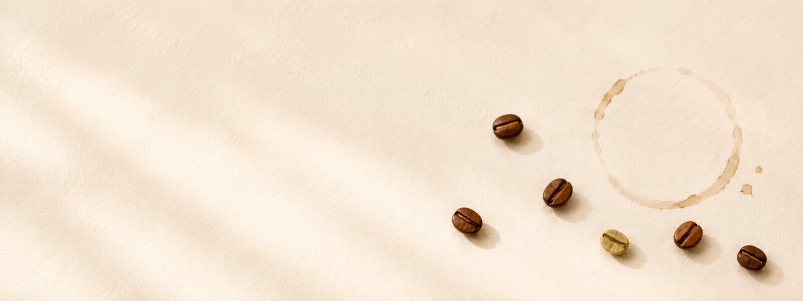 A few roasted beans and a faint coffee-ring stain on cream (illustration placeholder)